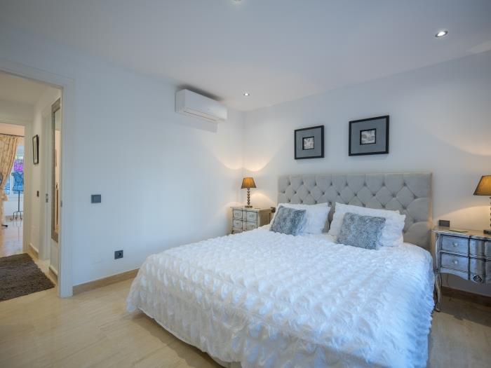 Double bed, nightstands with lamps and air conditioner in the guest bedroom