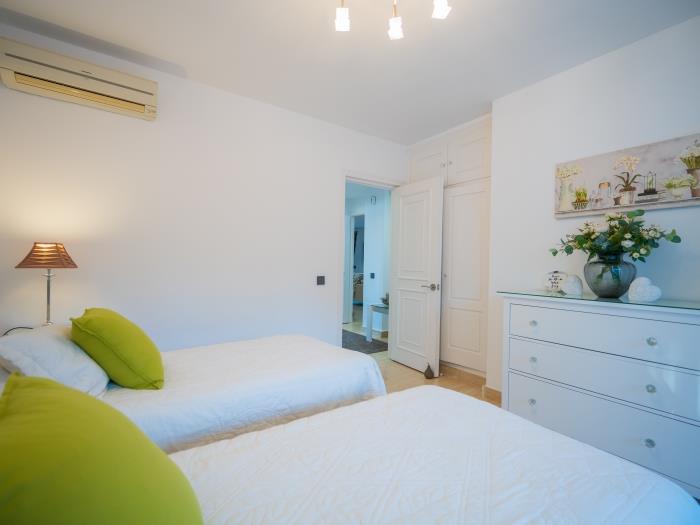 Two single beds, nightstands with lamps and an air conditioner in the guest bedroom