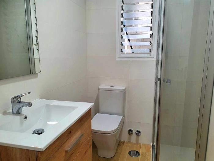 Family bathroom with walk-in shower, sink with mirror, and toilet