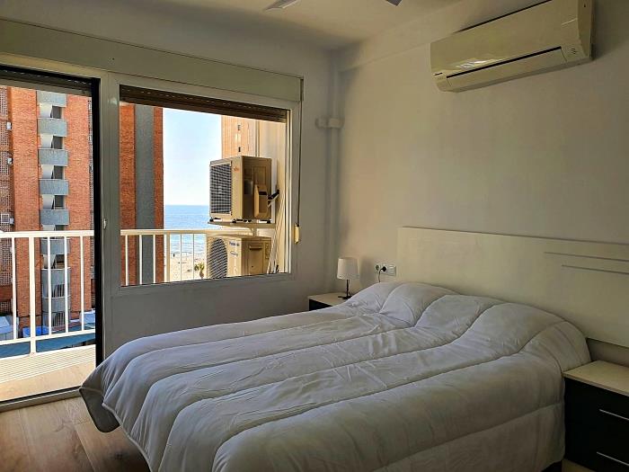 Bedroom with double bed, nightstands with lamps, airconditioner and exit to the terrace w sea views