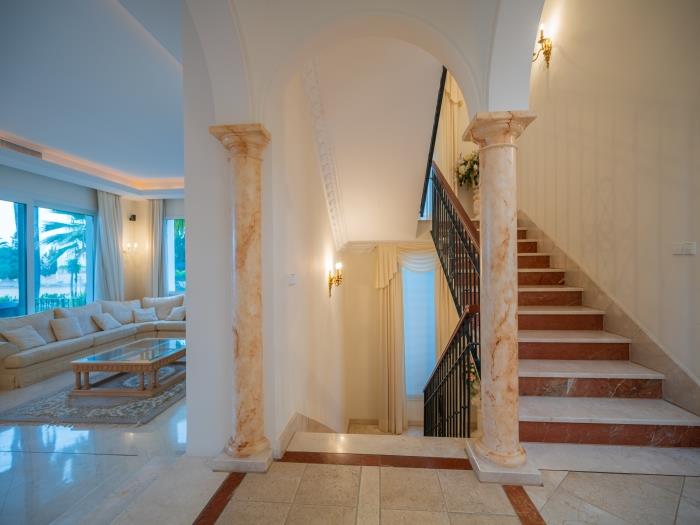 Elegant staircase with marble stairs, wrought iron and wooden balustrade
