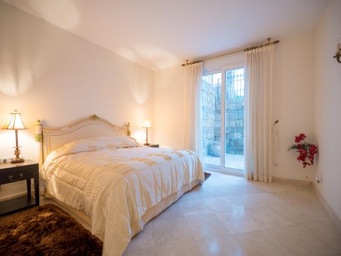 Bedroom with a double bed, nightstands with lamps, exit to the courtyard
