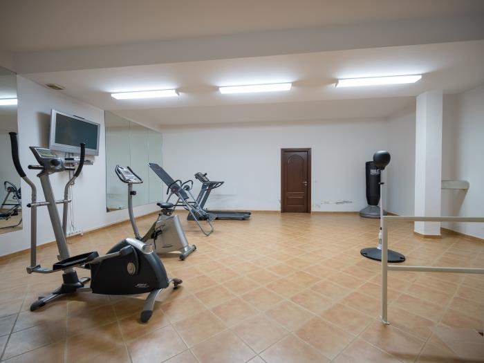 Gym equipped with a treadmill, bikes, ellipticals, dumbbells