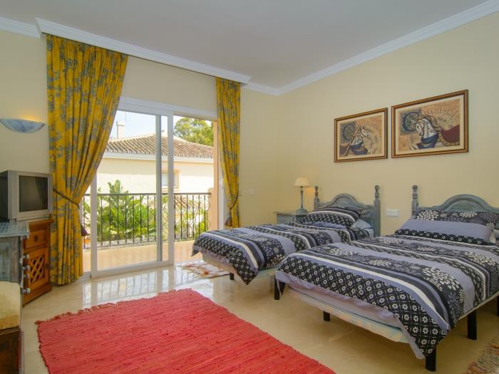 Guest bedroom with two single beds and access to the balcony through a sliding glass door