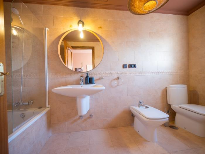 Bathroom with bathtub and rainhead shower, toilet, bidet and sink with mirror